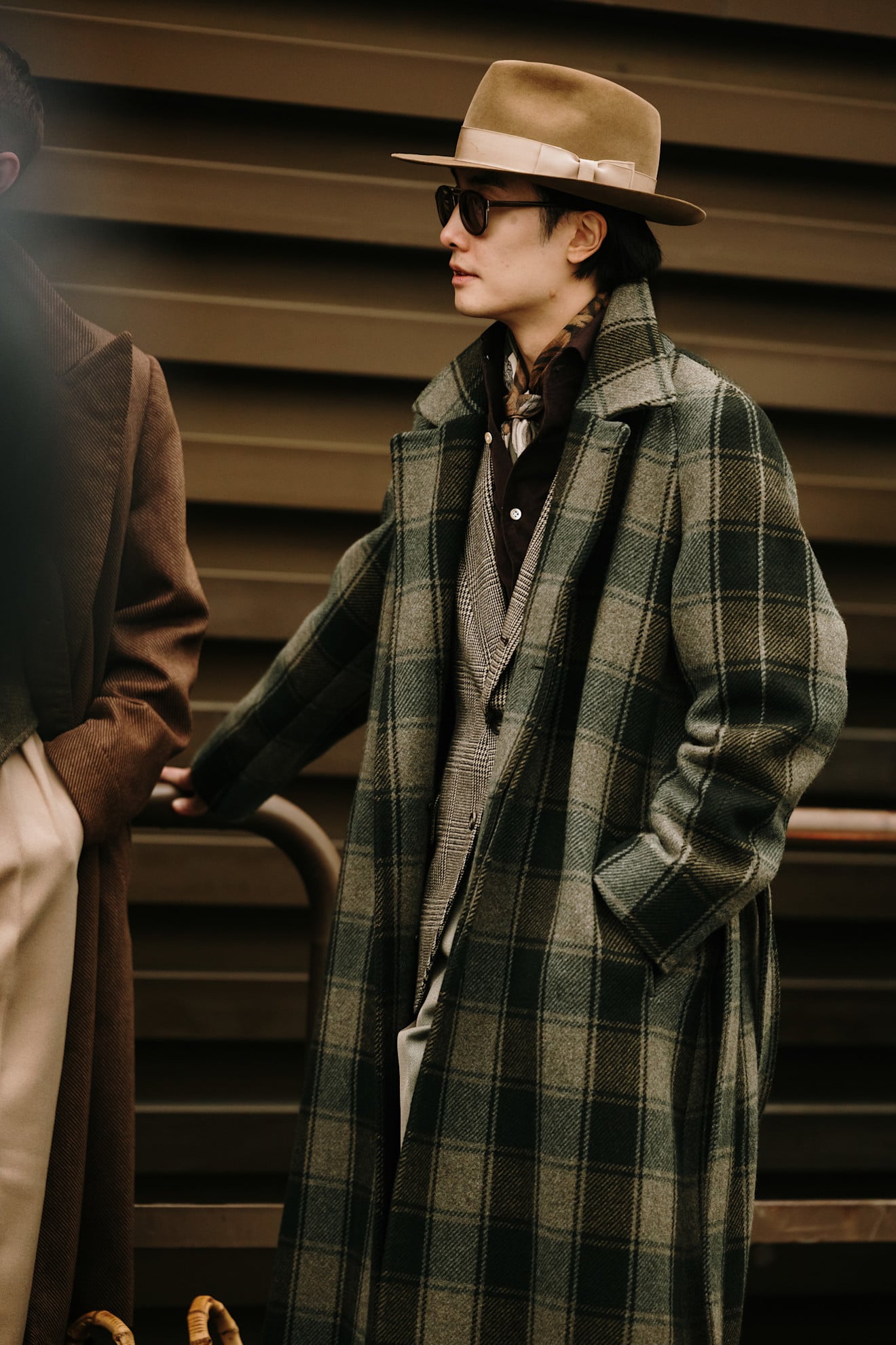 A man wearing a green and grey large check print double breasted jacket made of a thick wool material