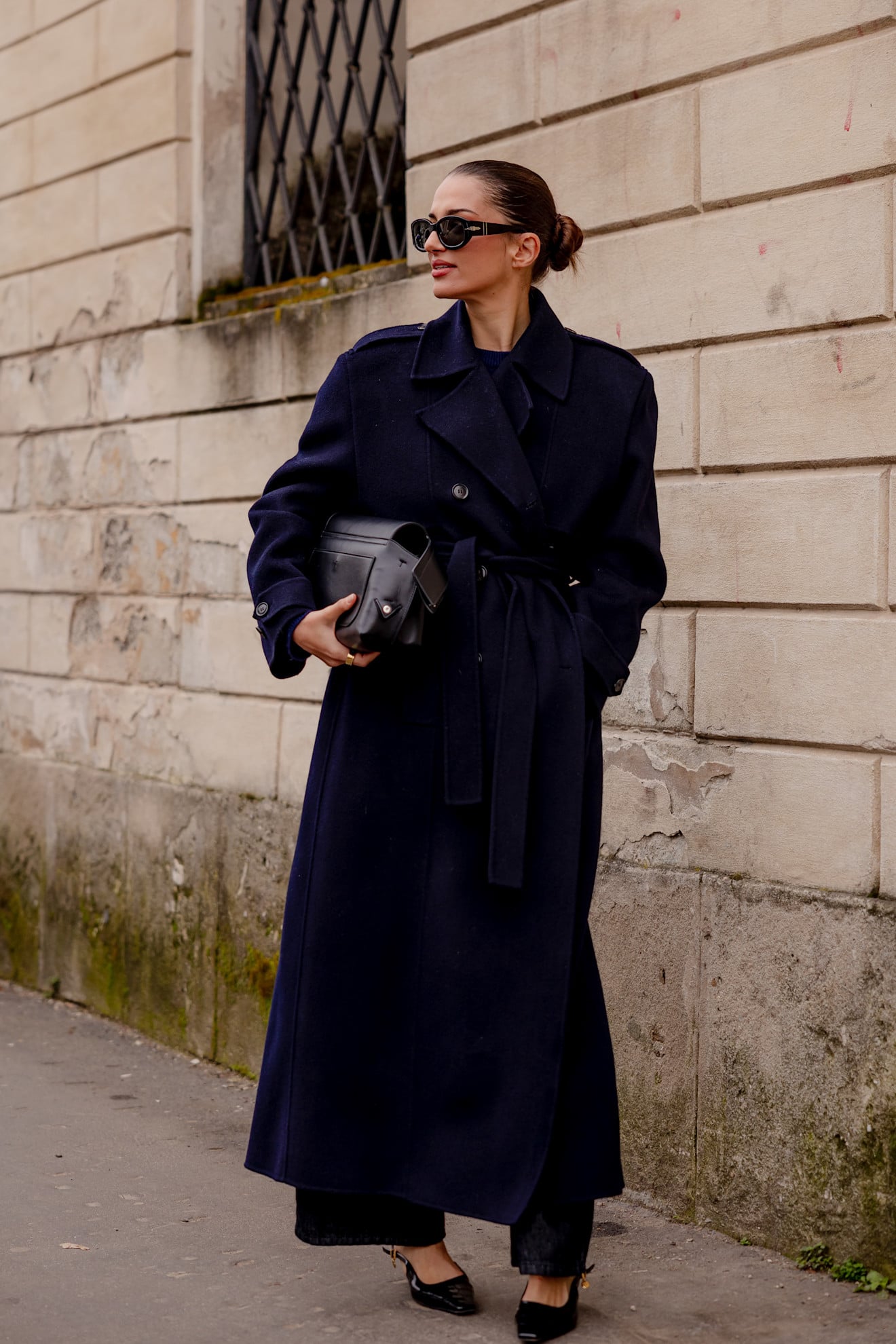 A woman wearing a classic wool trench coat in a dark midnight blue